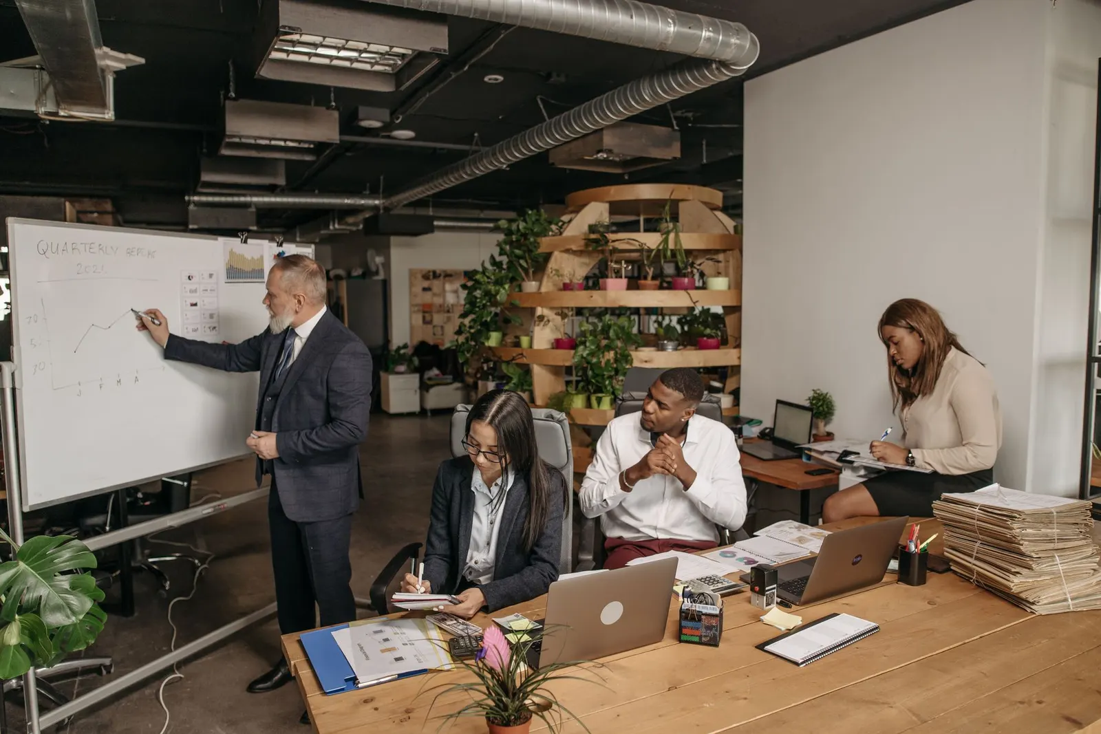 Colleagues gathered around a whiteboard in a bright office, the editorial team behind these cybersecurity program rankings