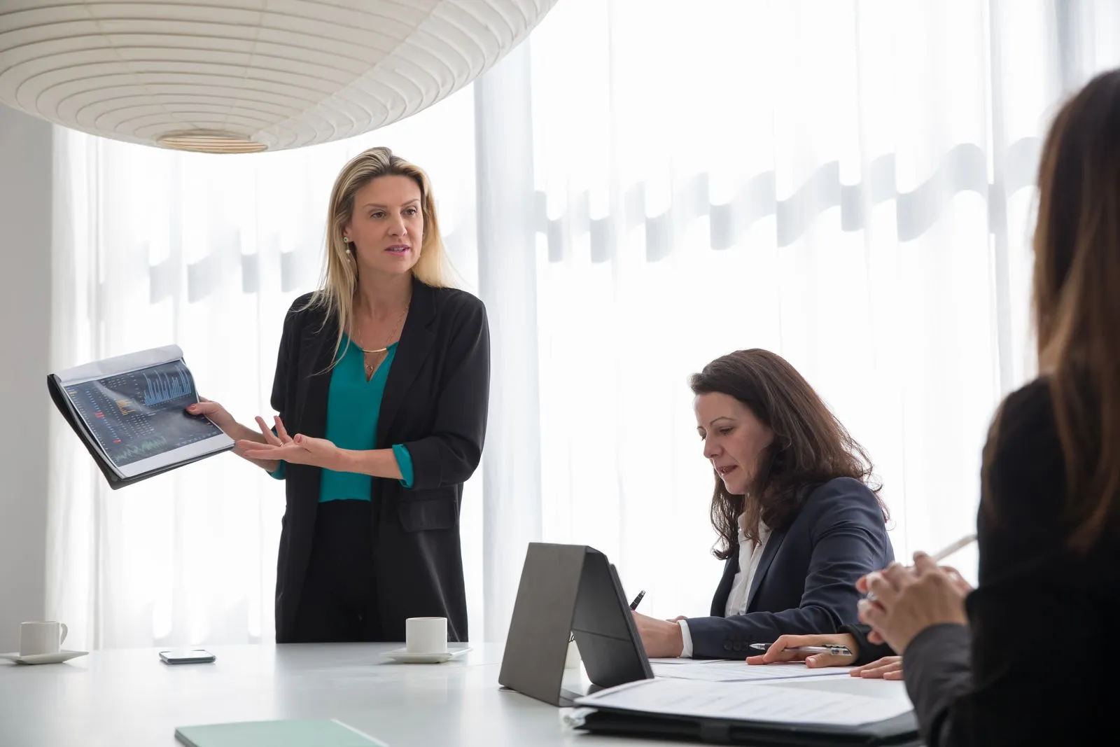 Businesswoman presenting a tablet to colleagues in a meeting about CISM certification and security management