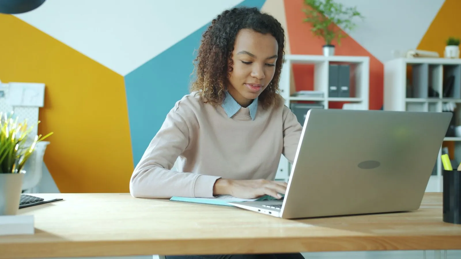 Young woman typing on a laptop at a bright desk while applying for entry-level cybersecurity jobs