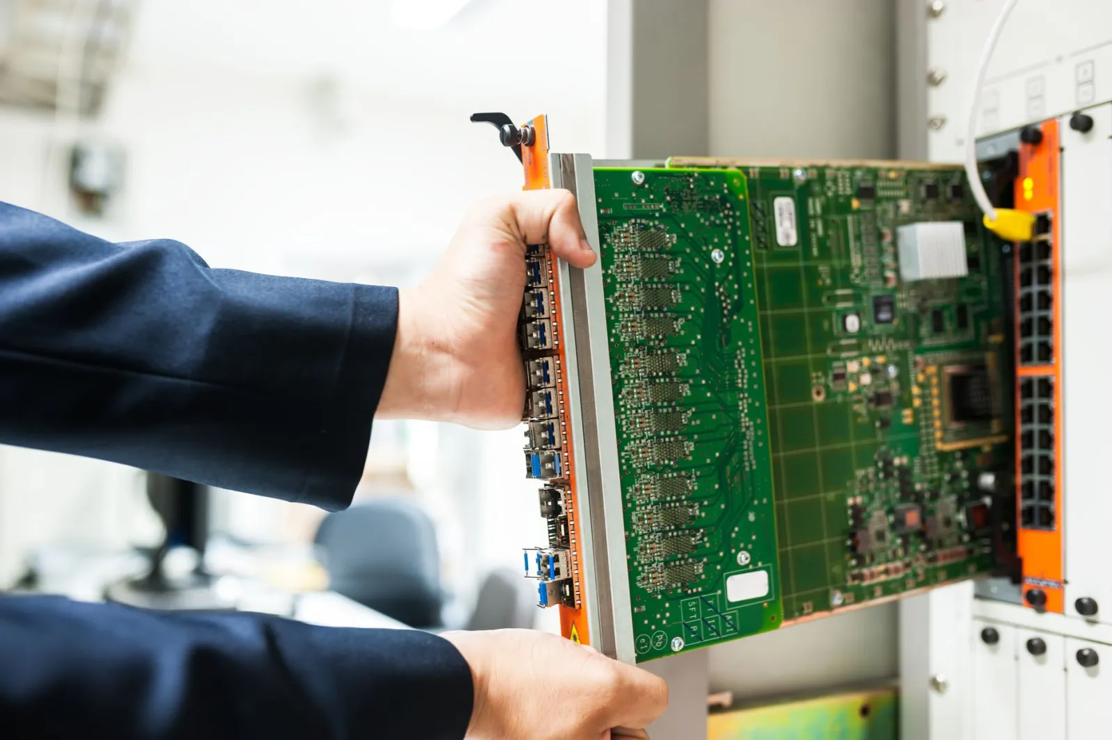 Network administrator in a navy jacket sliding a line card with network ports into a rack-mounted switch