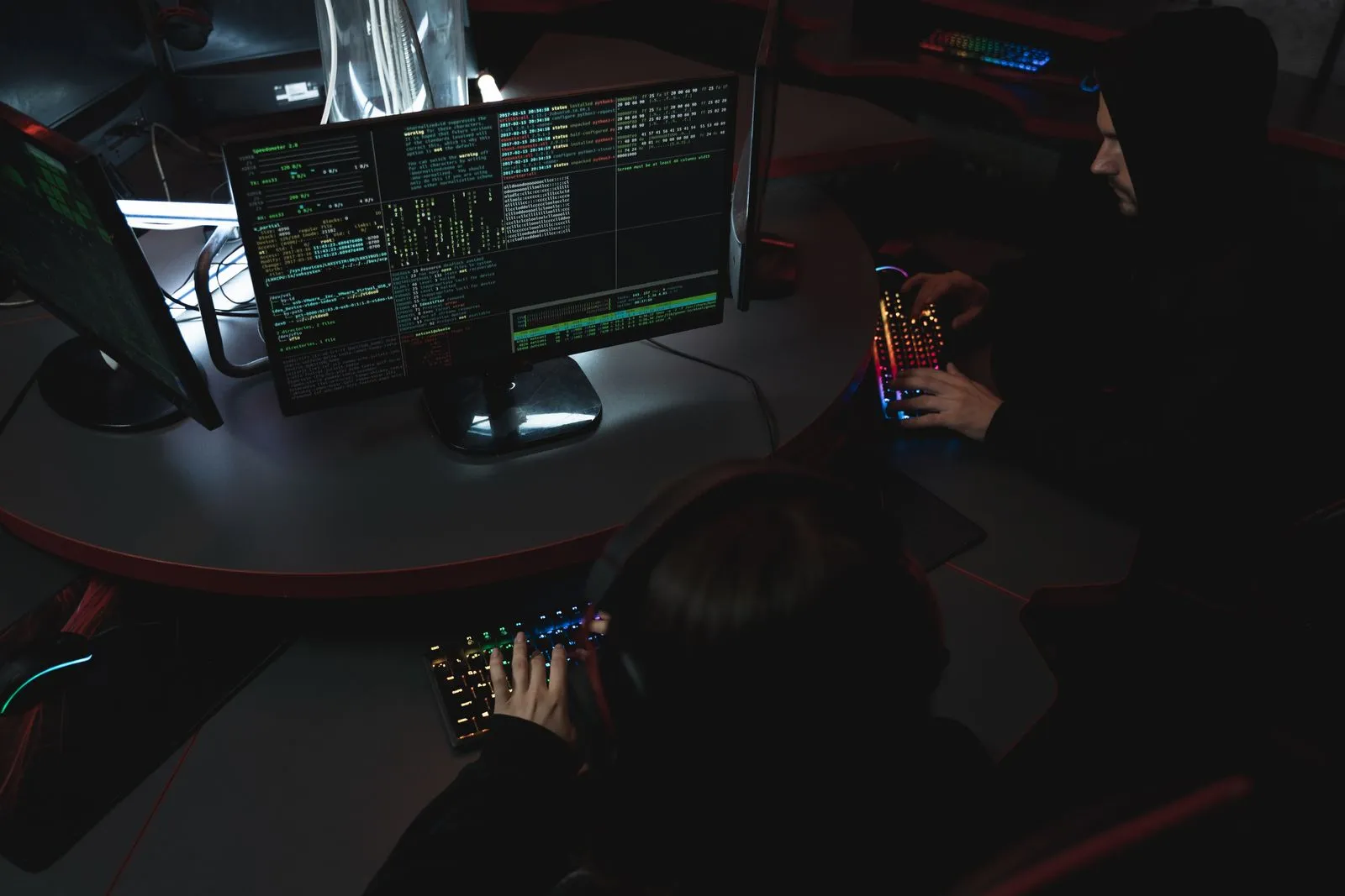 Two people at computers in a dim room, showing what you can do with a cybersecurity degree